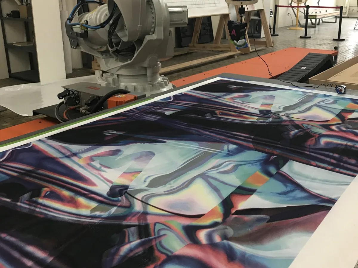 A large print by Anne Vieux on the bed beside a robotic arm